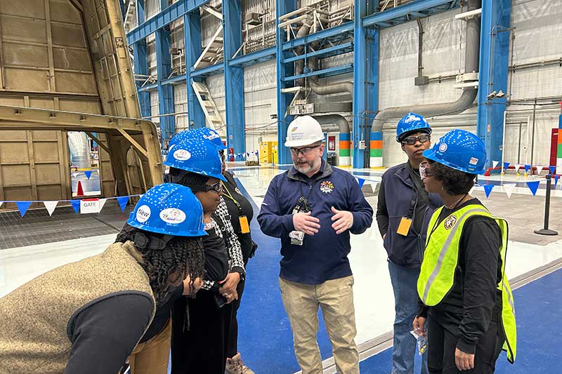 Team in hard hats discussing safety procedures inside a large industrial facility
