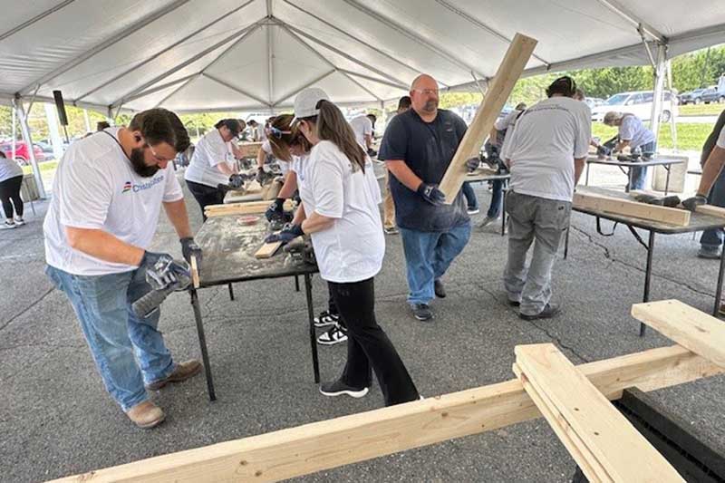 Calvert Cliffs volunteers under tent working on building a structure with wood and other materials