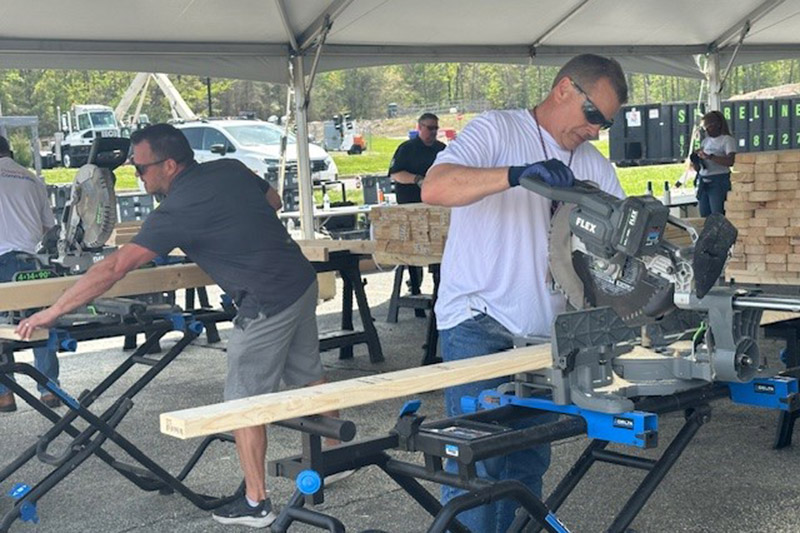 Two volunteers under tent doing construction work