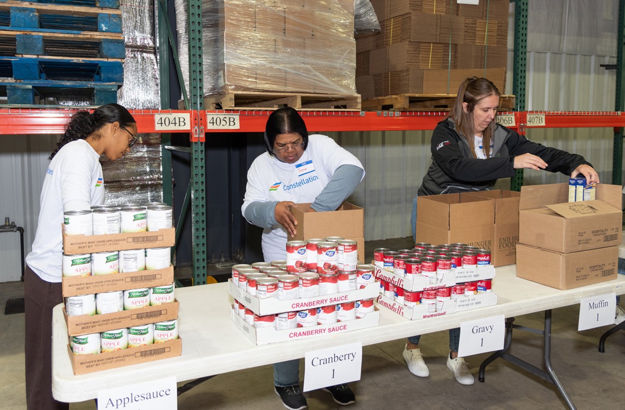 Constellation volunteers pack canned food into boxes at End Hunger Food Bank