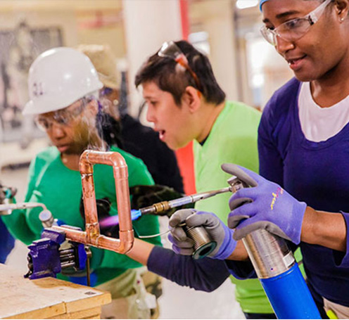 Chicago Women in Trades event with women working on pipes