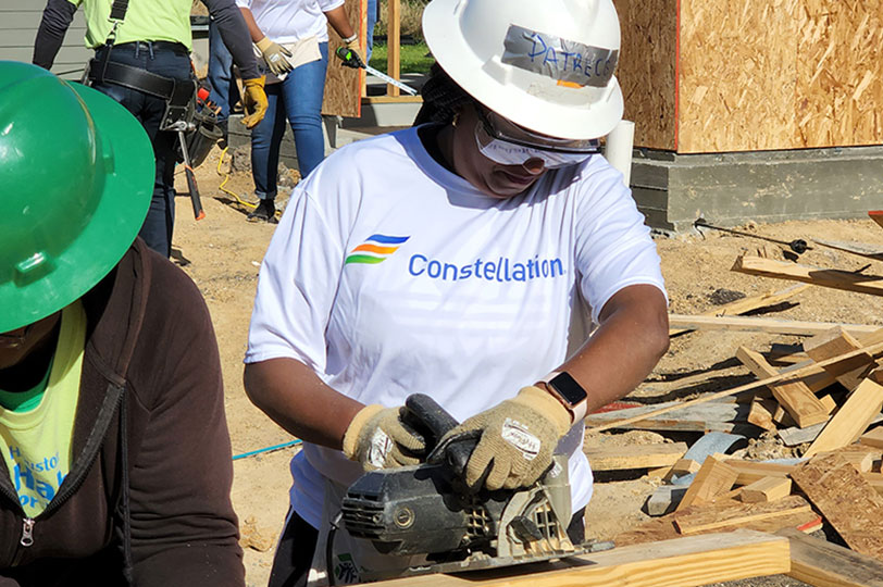 constellation volunteer sawing wood at powering communities event
