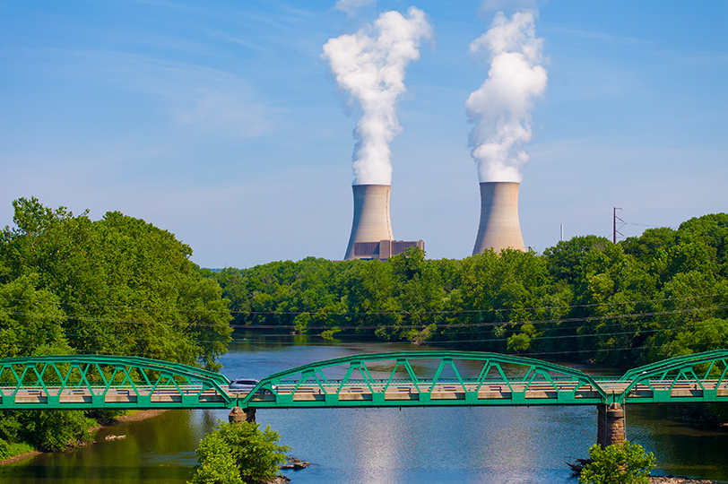 Two cooling towers in the distance with green bridge across waterway