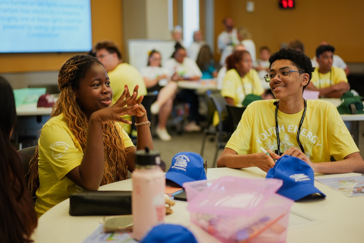 male and female y.e.s. students collaborating at a table with others in the background