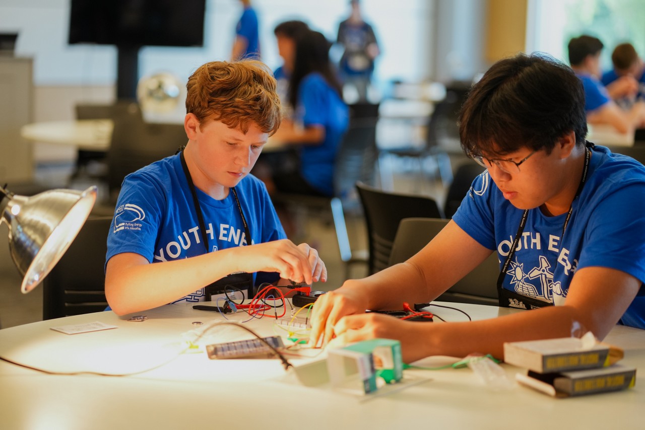 two male y.e.s. students sitting at a table working with concentration