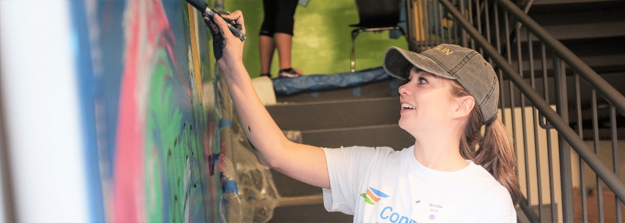 A constellation employee volunteering by painting inside school 